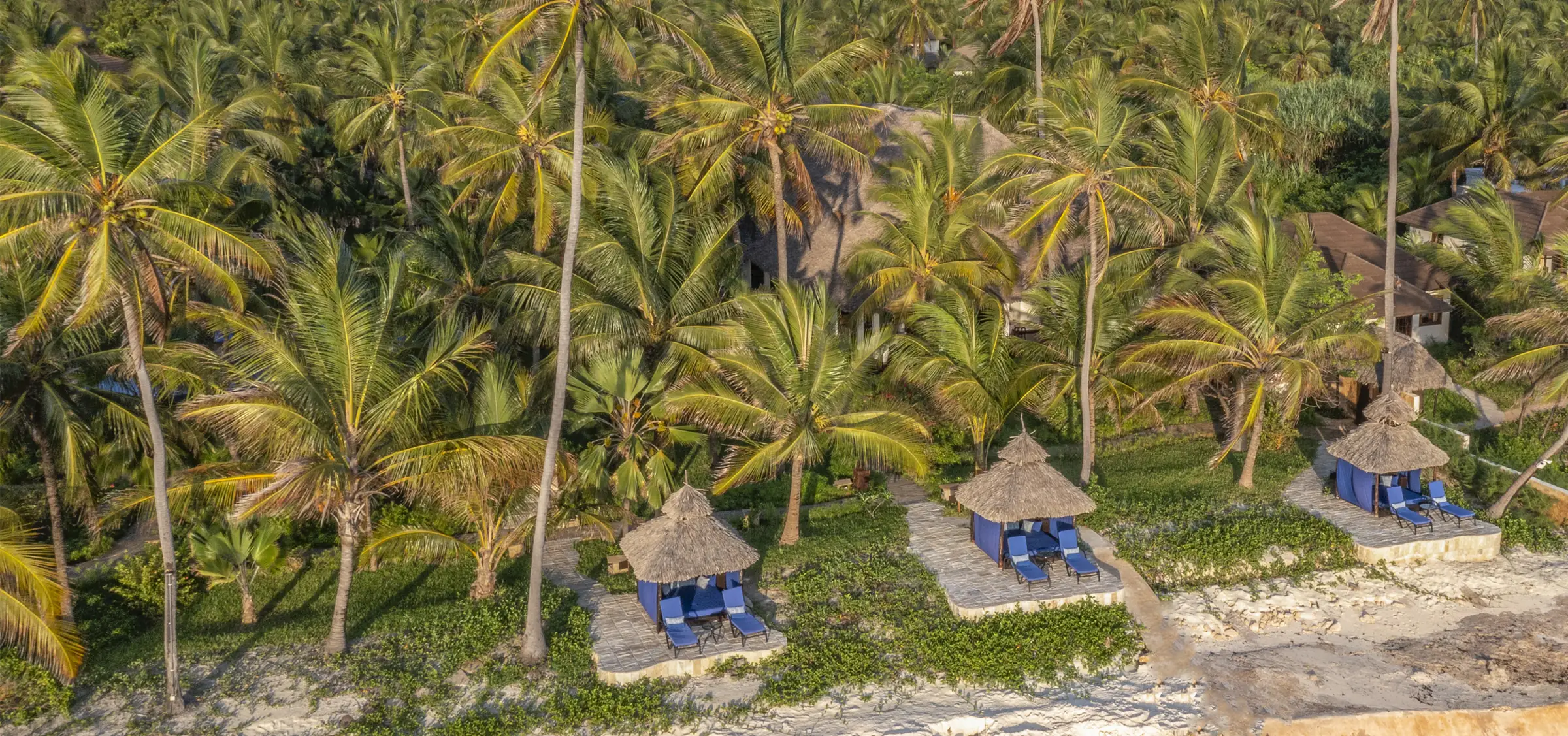 Strandkabiner bland palmerna vid The Palms i gyllene kvällsljus