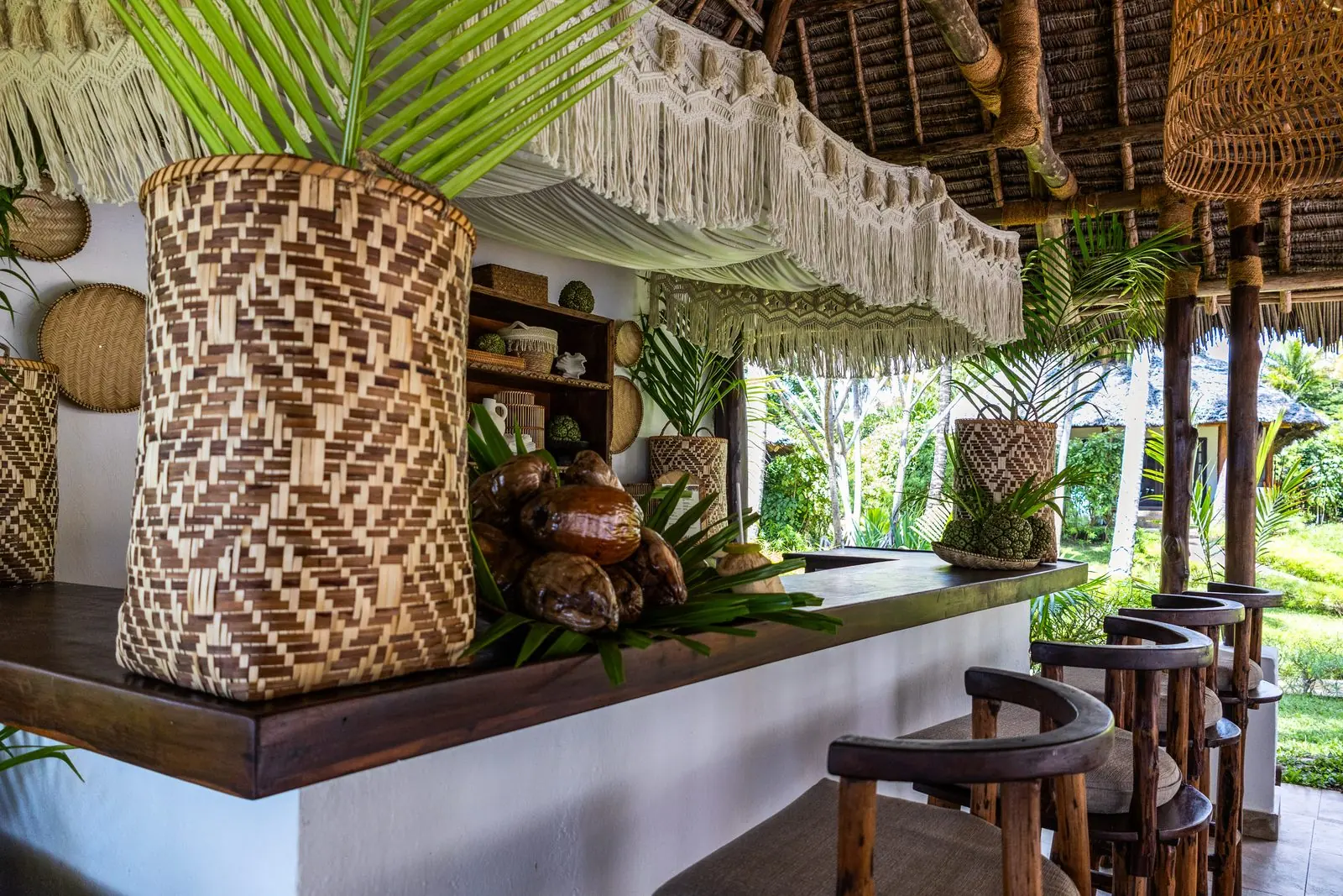 Poolbaren på The Palms med flätade korgar, makramé och barstolar under halmtaket